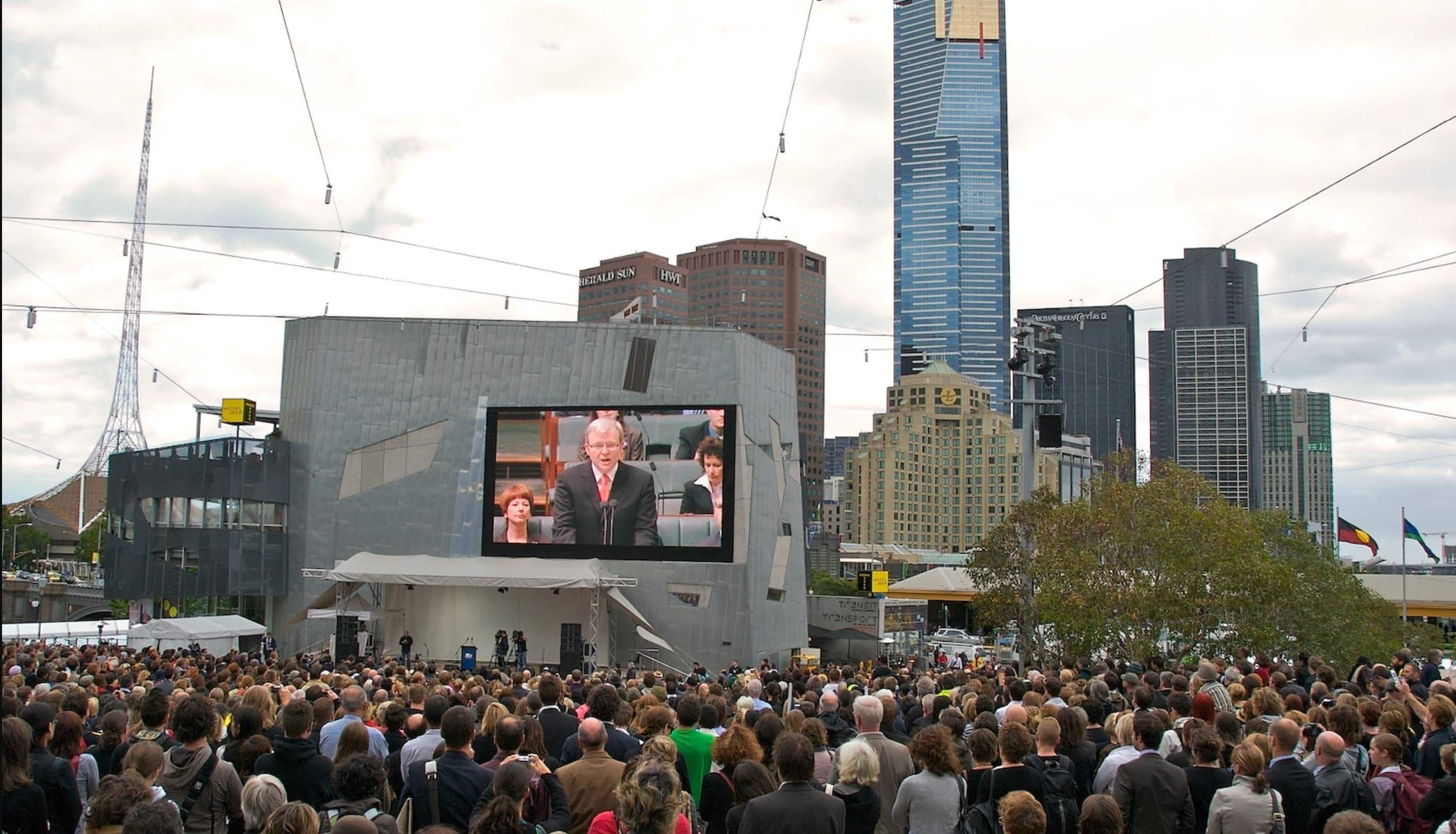 Crowd watches Australian Prime Minister Kevin Rudd deliver “National Apology to the Stolen Generations.” Photo by Virginia Murdoch February 13, 2008 via Flickr, CC BY-SA 2.0..